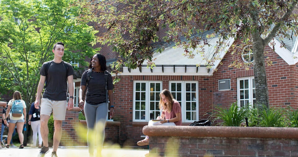 Two students talk as they walk by residence halls