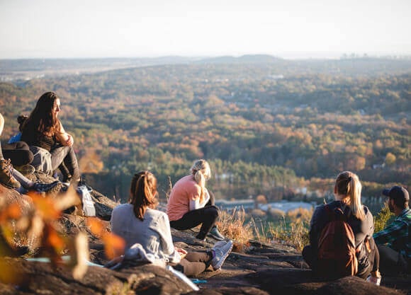 A group of students sit on the top of Sleeping Giant during a Reflective Hike to Yoga session.