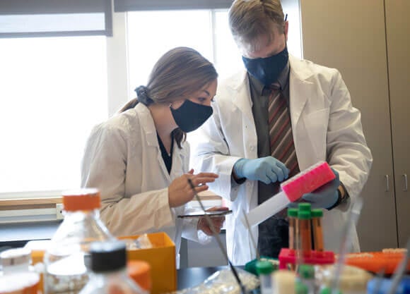 A graduate student works with a professor in a biomedical sciences lab