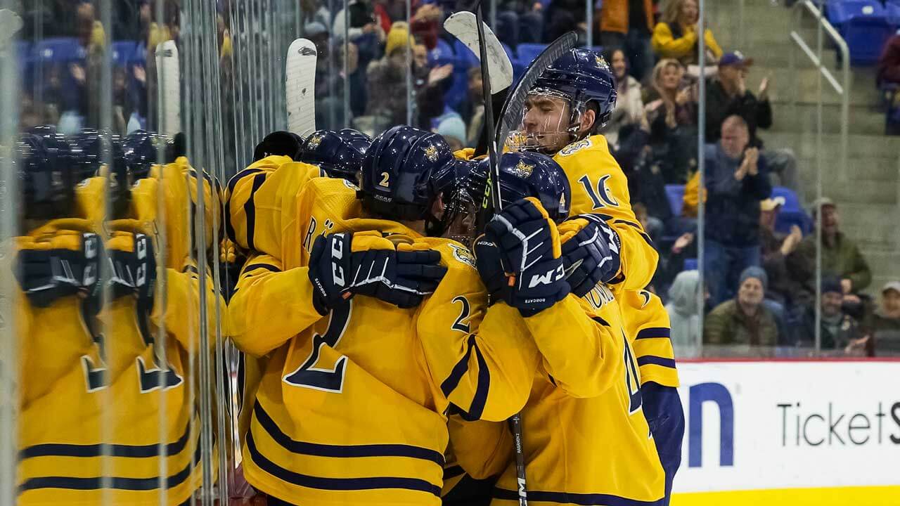 Quinnipiac men's ice hockey players cheer and hug after winning a game
