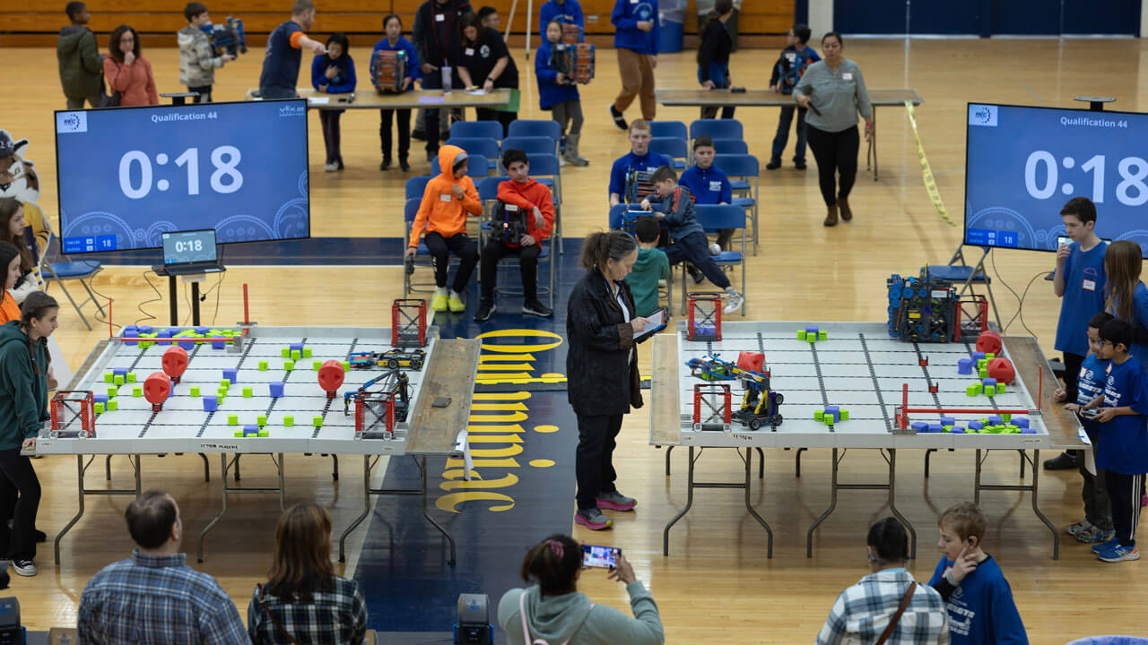 An aerial view of students sitting and waiting to particpate in robotics event in Burt Kahn Court Quinnipiac University