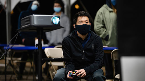 A student wearing a face covering plays Super Smash Bros