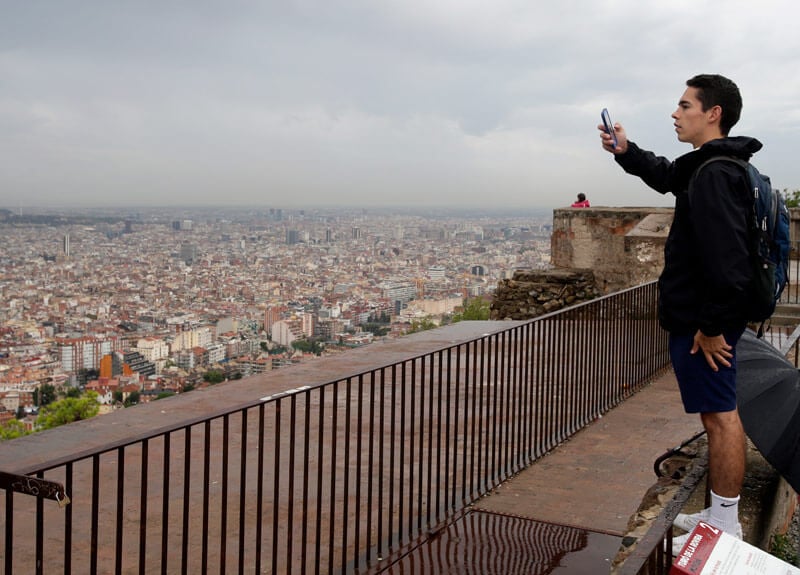 A student takes a photo of Barcelona from a high vantage point.