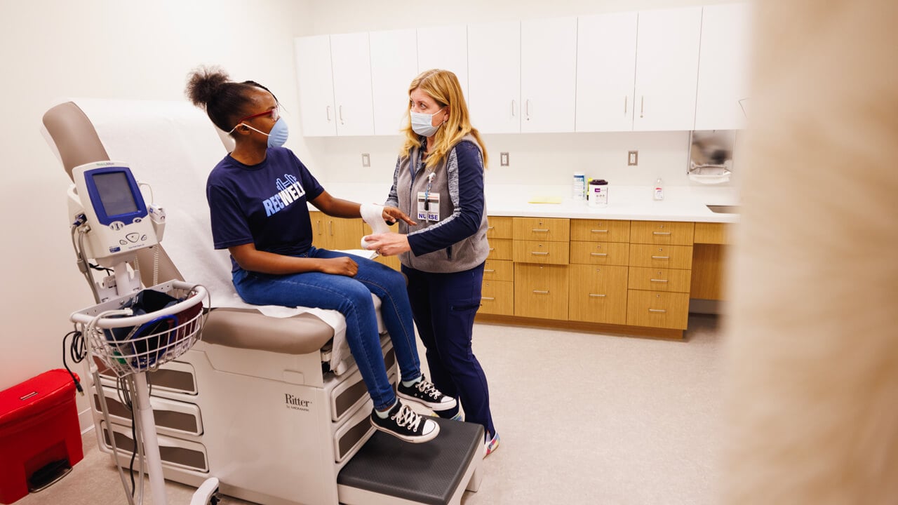 A health care provider evaluates a student in a student health services exam room