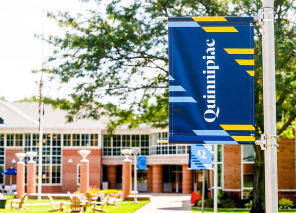 Quinnipiac banner hangs above the quad on a sunny summer day