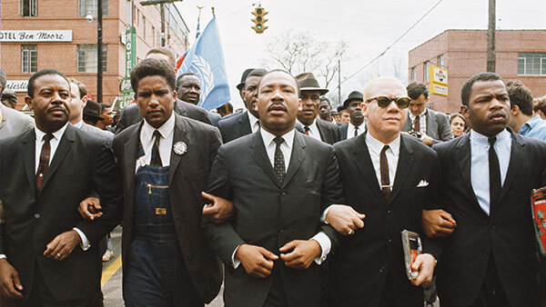 Martin Luther King, Jr. marches arm in arm with others in Montgomery, Alabama.