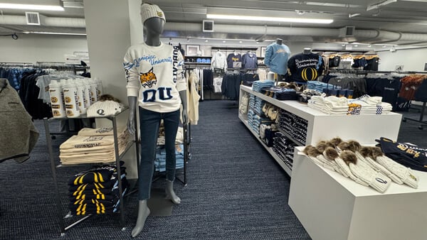 A mannequin wearing Quinnipiac merchandise among shelves of other clothing