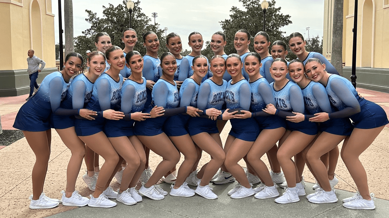 A group photo of Quinnipiac Dance Team in uniform posing at the ESPN World Wide of Sports in Florida.