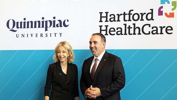 Quinnipiac President Judy Olian and Jeffrey A. Flaks, president and chief executive officer of Hartford HealthCare, announce a strategic partnership between the organizations at the university's North Haven Campus.