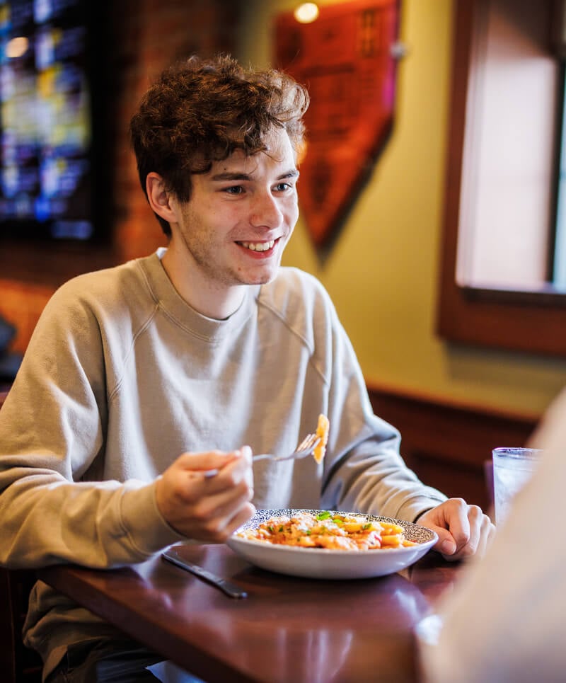A Quinnipiac student eats a pasta dish in a local restaurant with his family