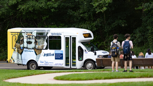 Students waiting at a shuttle stop on the Mount Carmel Campus at Quinnipiac