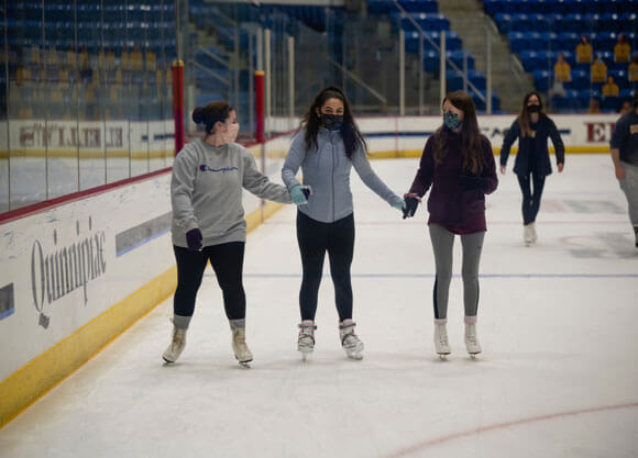 Students holding hands and skating on ice in people's united