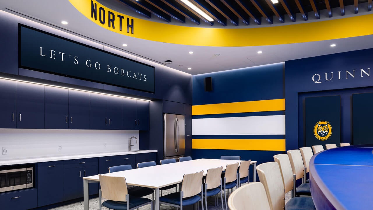 Large table and chairs set up in the men's ice hockey locker room.
