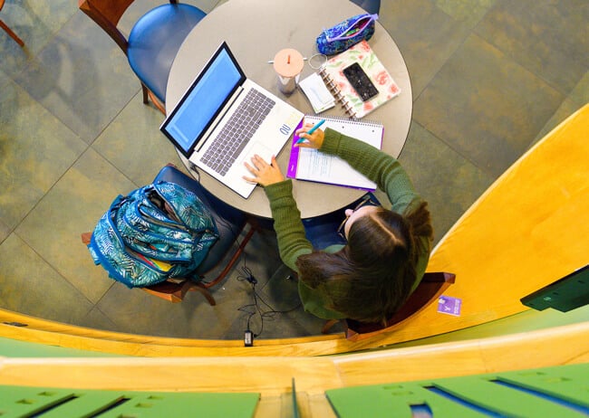 A student works at her laptop in the student center piazza