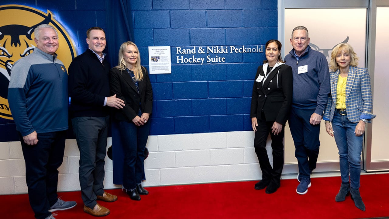 Dignitaries smile outside the newly named Rand and Nikki Pecknold Hockey Suite.