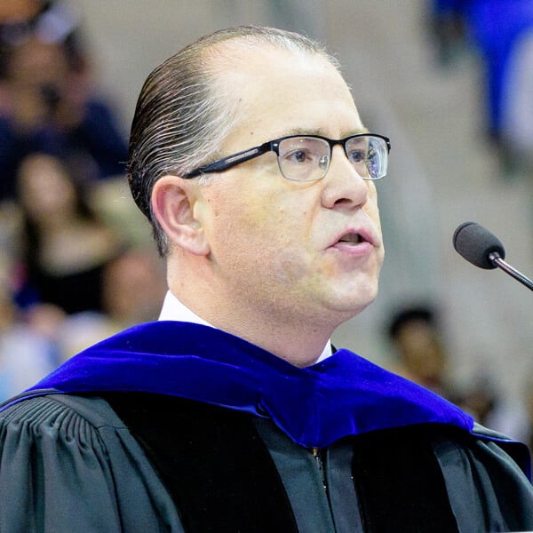 Headshot of Stam Bizanis speaking at a podium.