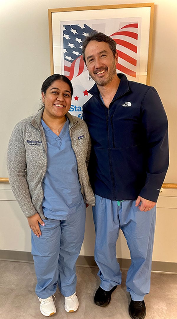 Dr. Dennehy and Zeel Patel pose for a photo in their hospital scrubs