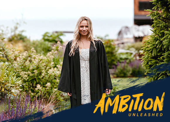 Ambition Unleashed: Mckenna Haz wears her commencement robe outside in a field of flowers