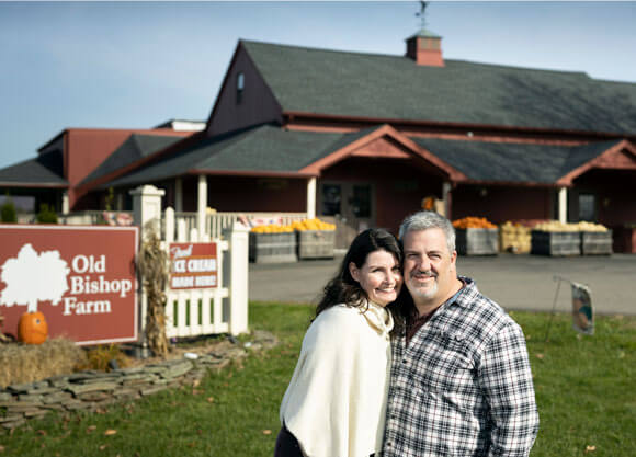Carolyn and John Torello stand in front of the Old Bishop Farm sign in Cheshire, CT