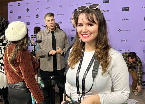 Casey Nedelka on the red carpet with a camera around her neck at Sundance Film Festival