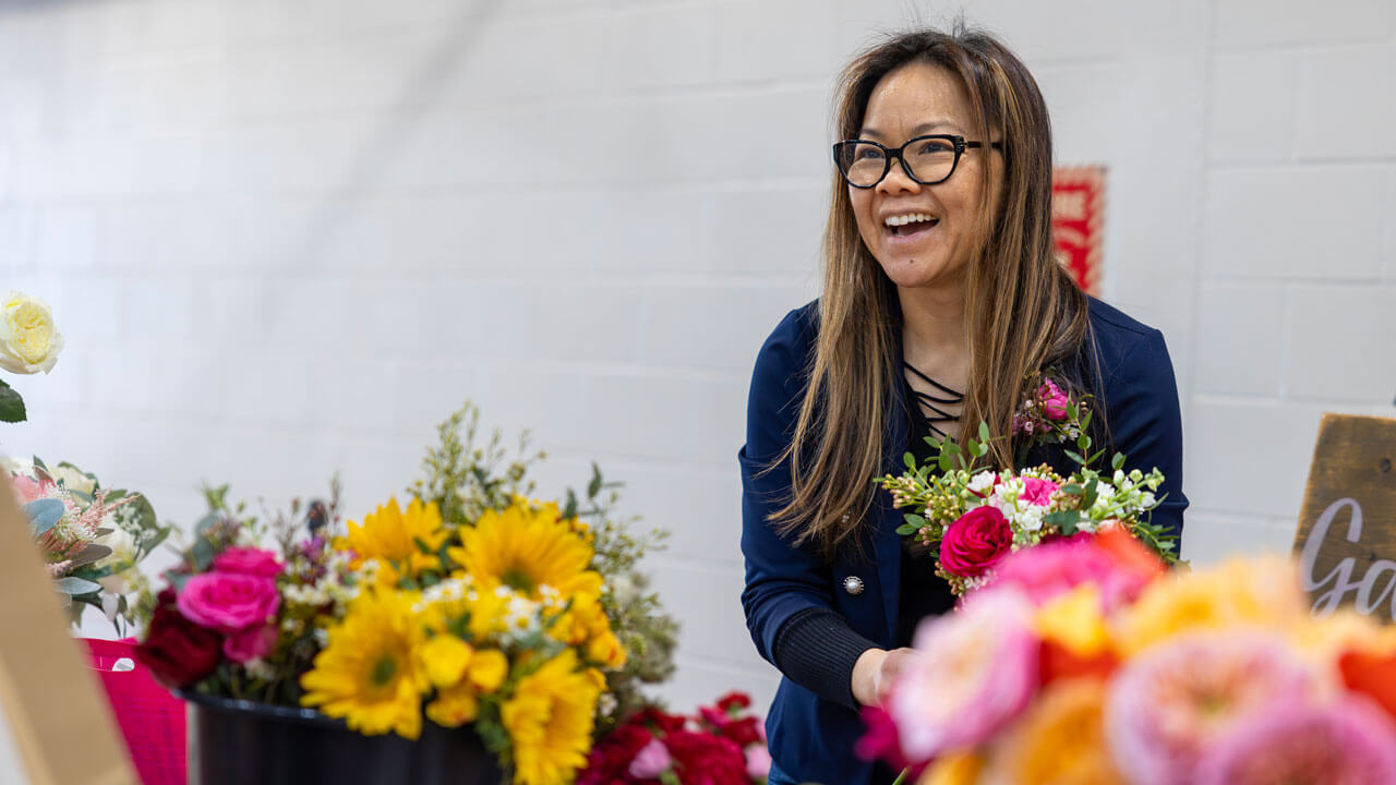 A vendor smiles and sells flowers.