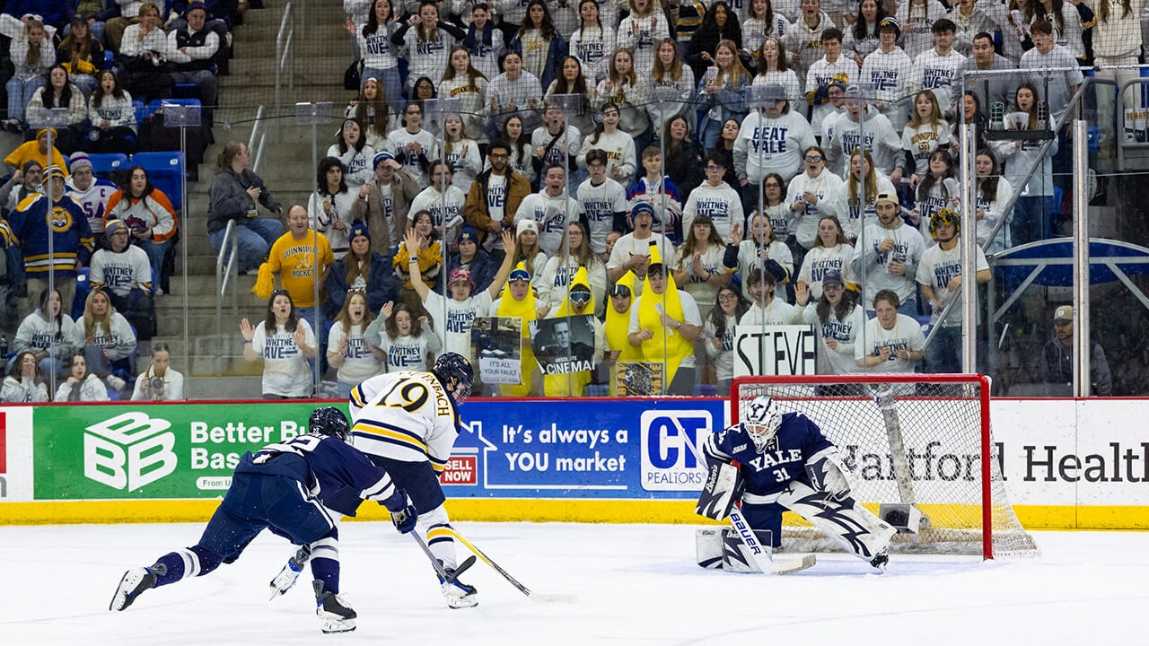 Men's ice hockey player skating towards goal with the puck