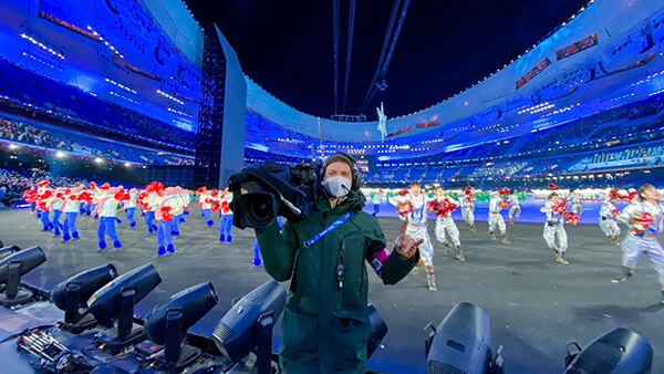 Matt Andrew holds a camera while filming the Opening Ceremony of the winter Olympics in Beijing.