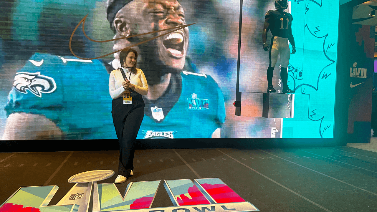 Carly MacManus poses in front of an interactive experience of screens at Super Bowl LVII press week.