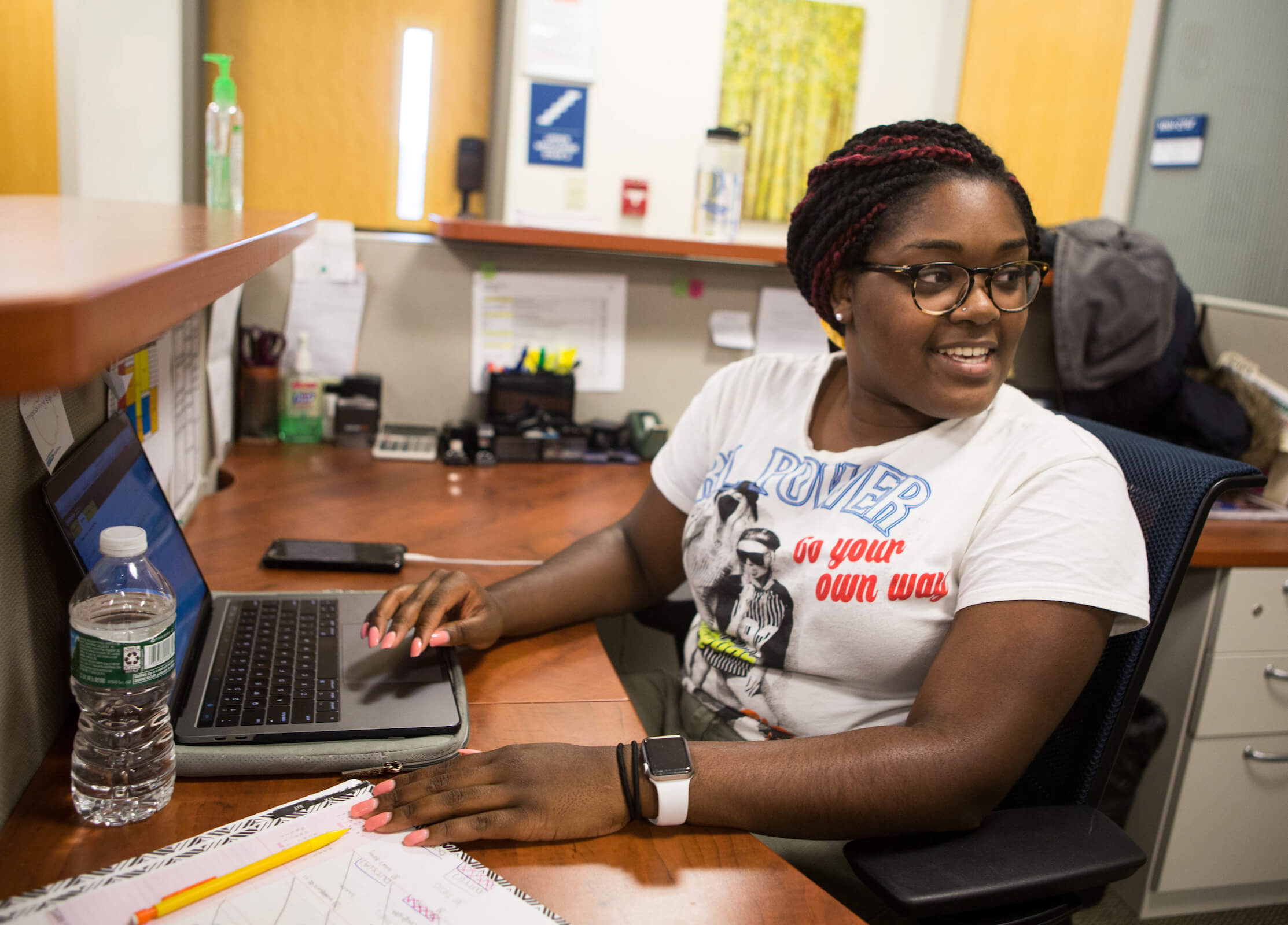 Student Cynthia Clemont sitting at a desk in front of a laptop in the Graduate Student Affairs Office.