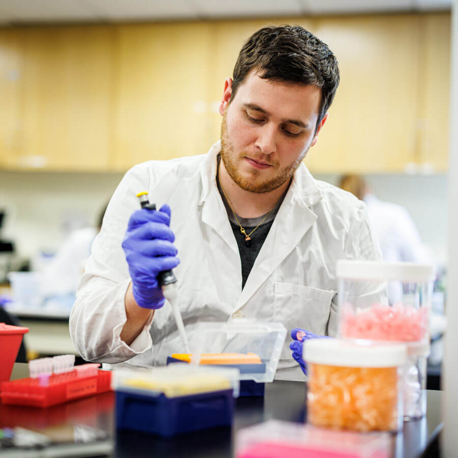 A male student works with a pipette