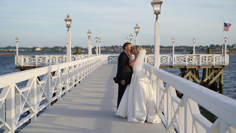 Nicole Trotta and Rosario Giliberto kiss from a dock on their sunny wedding day