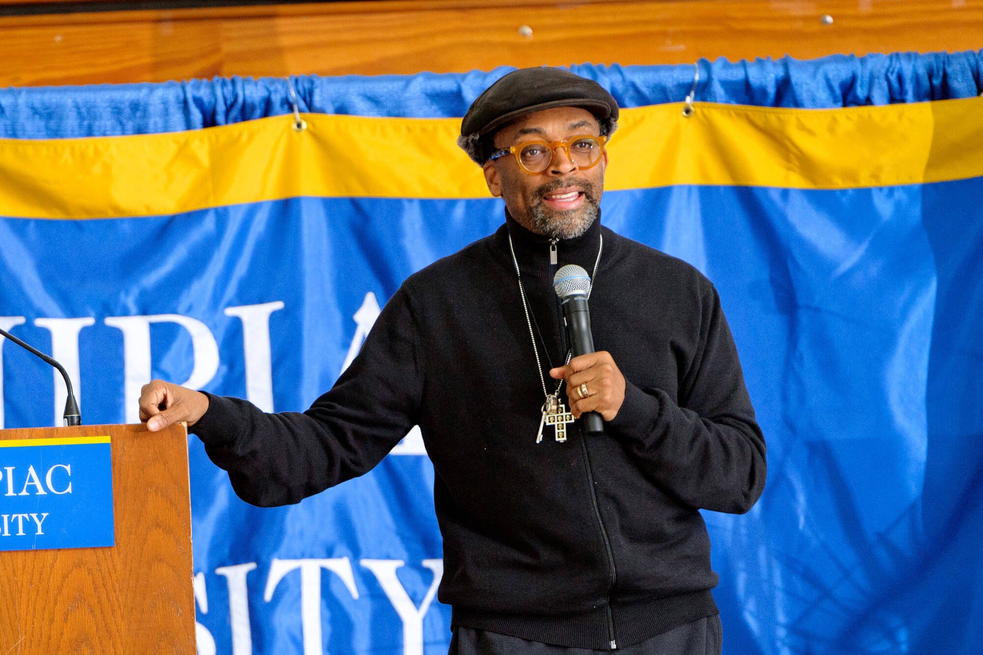 Spike Lee speaks in front of a Quinnipiac sign during a black history month event