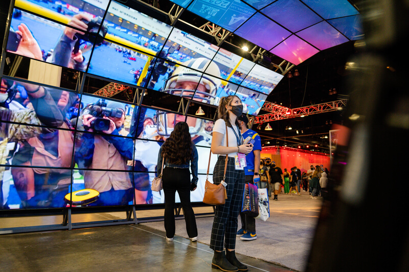 A student stands under an colorful display of TV screens