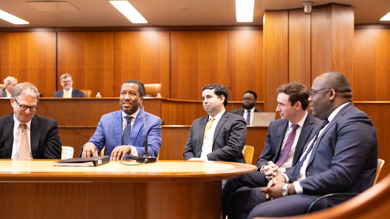 Panel at the front of a courtroom talking amongst themselves