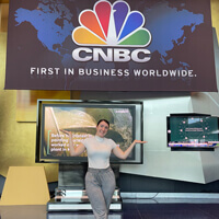 Melanie Careri posing under a CNBC digital sign