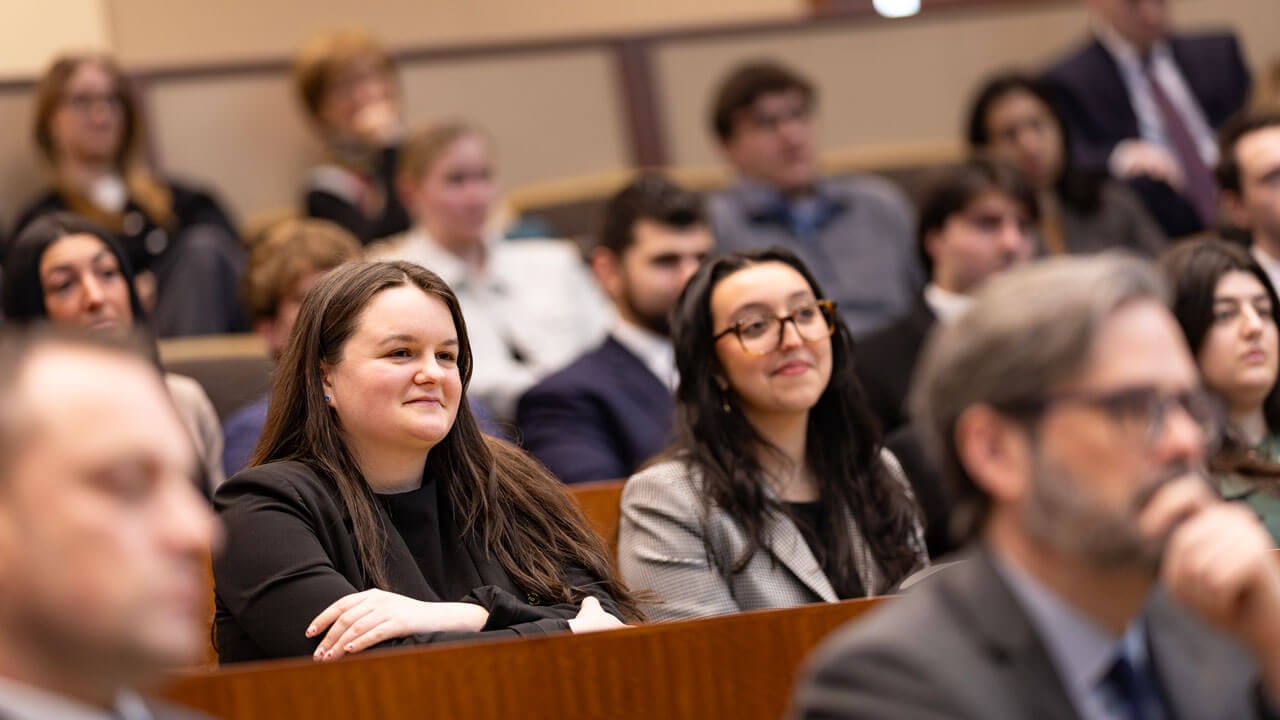 Crowd members look intensely towards the front of the courtroom