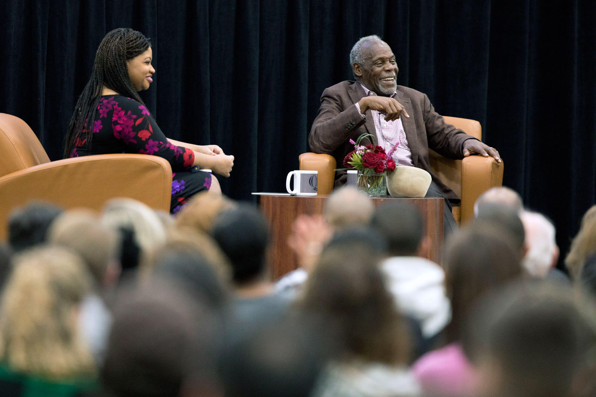 Danny Glover and Khalilah Brown-Dean speak on stage in front of an audience.