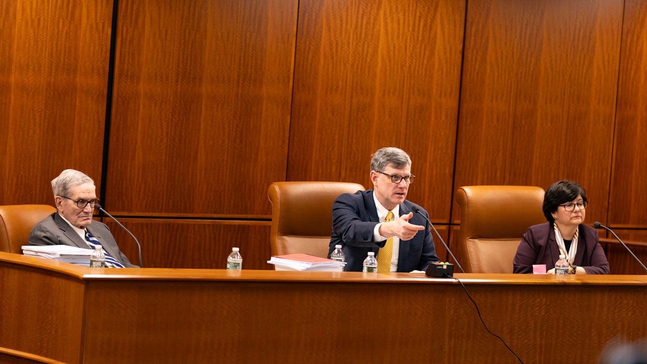 Judge and 2 others talking at the front of the courtroom