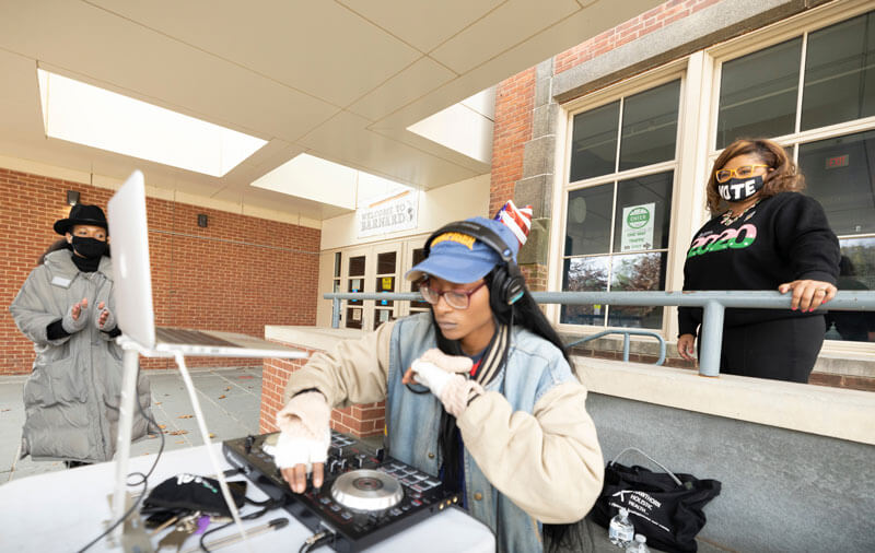 Khalilah Brown-Dean stands behind a DJ entertaining voters on election day
