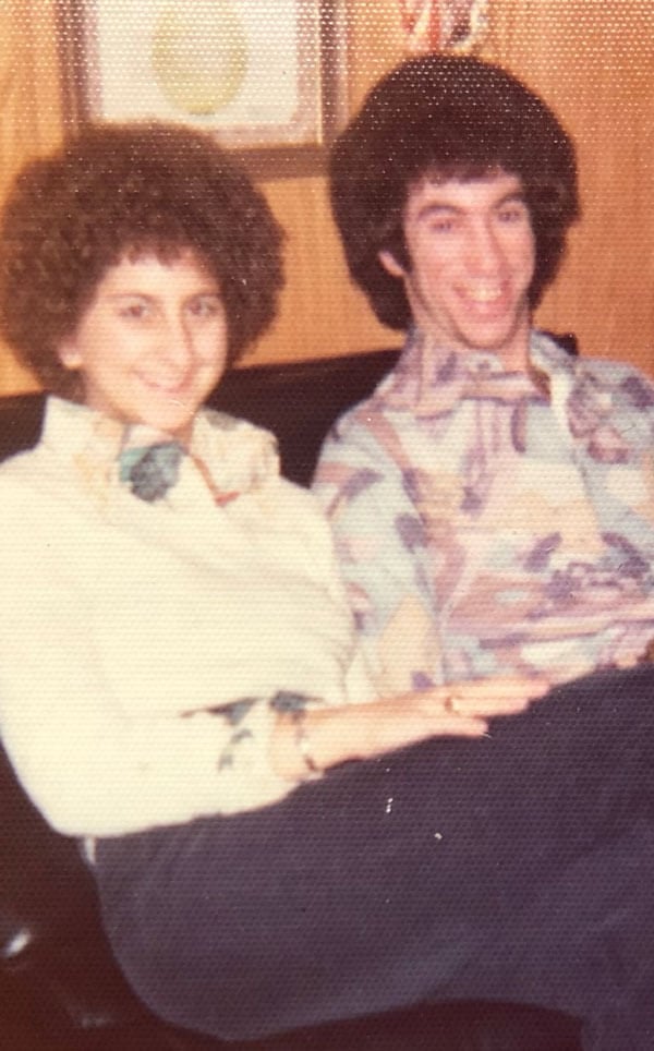 Richard and Vicki Horowitz both smile on a couch with big hairstyles in 1975.