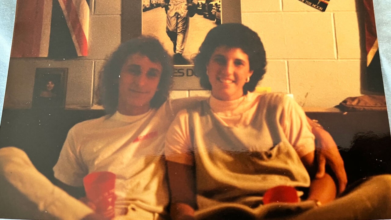Jeff and Christina Philibert smile on a couch with big hair, an old photo.