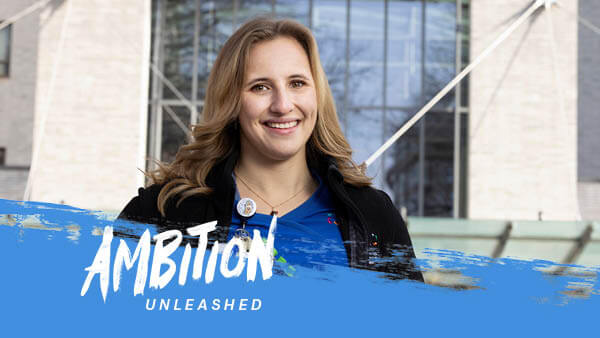 Ambition Unleashed: Emma Raboin stands in front of Hartford Hospital dressed in scrubs.