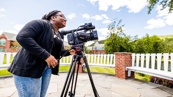 Communications student operates a video camera on campus.