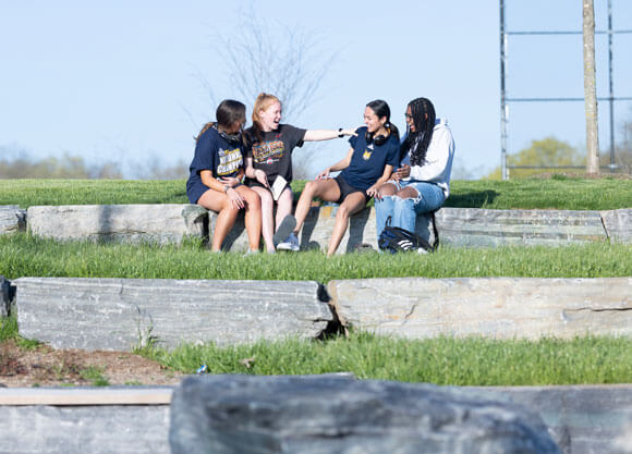 Students sit at the pavilion by the Recreation and Wellness Center laughing