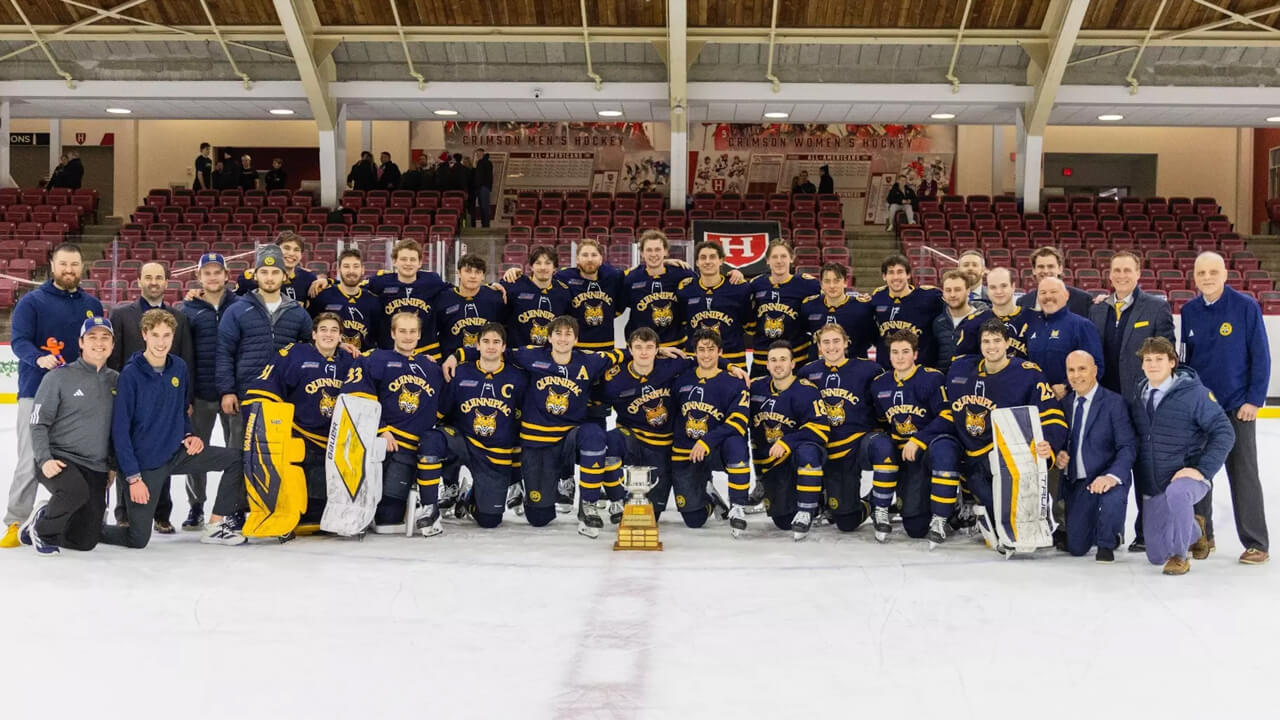 Men's ice hockey team and coaches on the ice with the Cleary Cup trophy