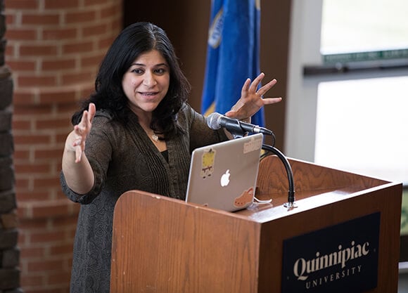 A professor gestures behind a podium.