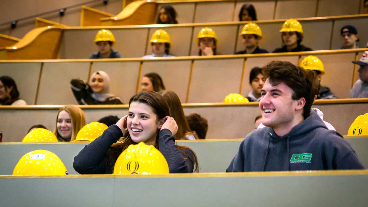 A male and a female student sitting with their hard hats in front of them