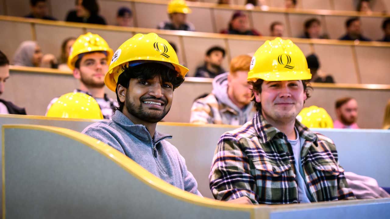 2 male students sitting while wearing their hard hats