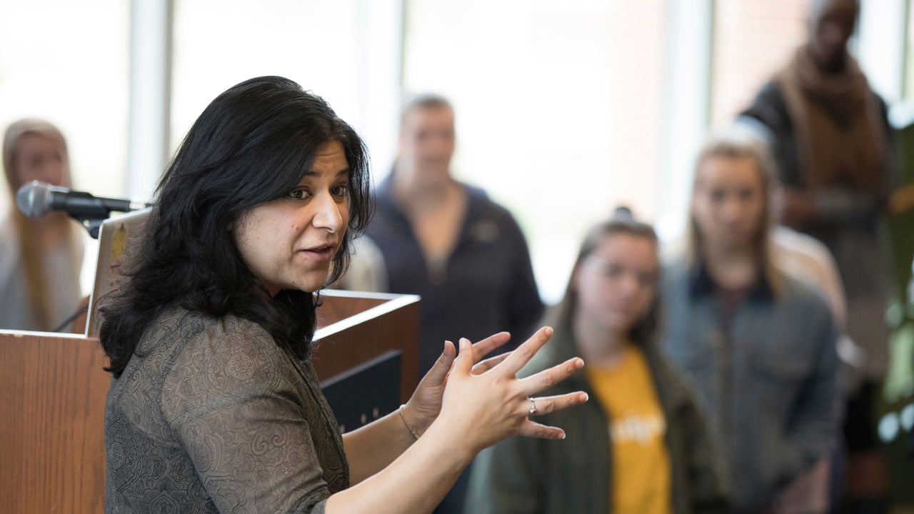 A professor gestures as she speaks to a group of students