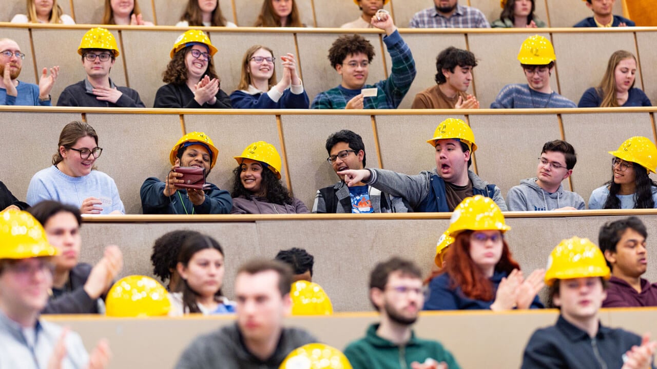 Students smile after receiving their hard hats